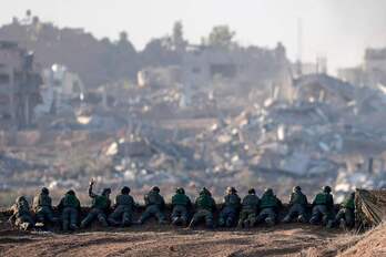 Soldados israelíes apostados frente a un barrio gazatí destruido.