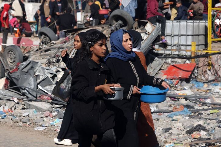 Dos jóvenes palestinas refugiadas en Rafah portan agua en sendos recipientes. 