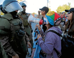 Una manifestante que celebra la victoria del no, ante un policía.