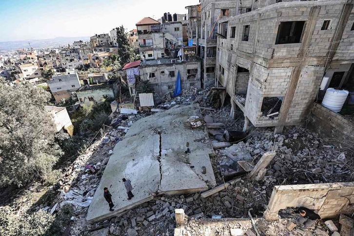 Varios hombres, entre los escombros de un edificio destruido durante una incursión del Ejército israelí en el campo de refugiados de Yenin.