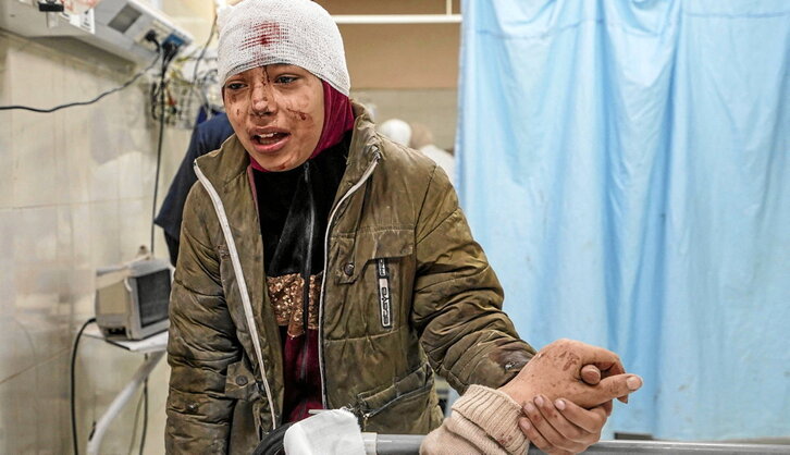 Un niña coge la mano de su madre, ambas heridas en un bombardeo israelí en Jan Yunis.