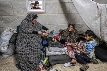 Dos mujeres y un niño comparten una comida en un campamento improvisado del hospital de Khan Yunis, en el sur de Gaza.