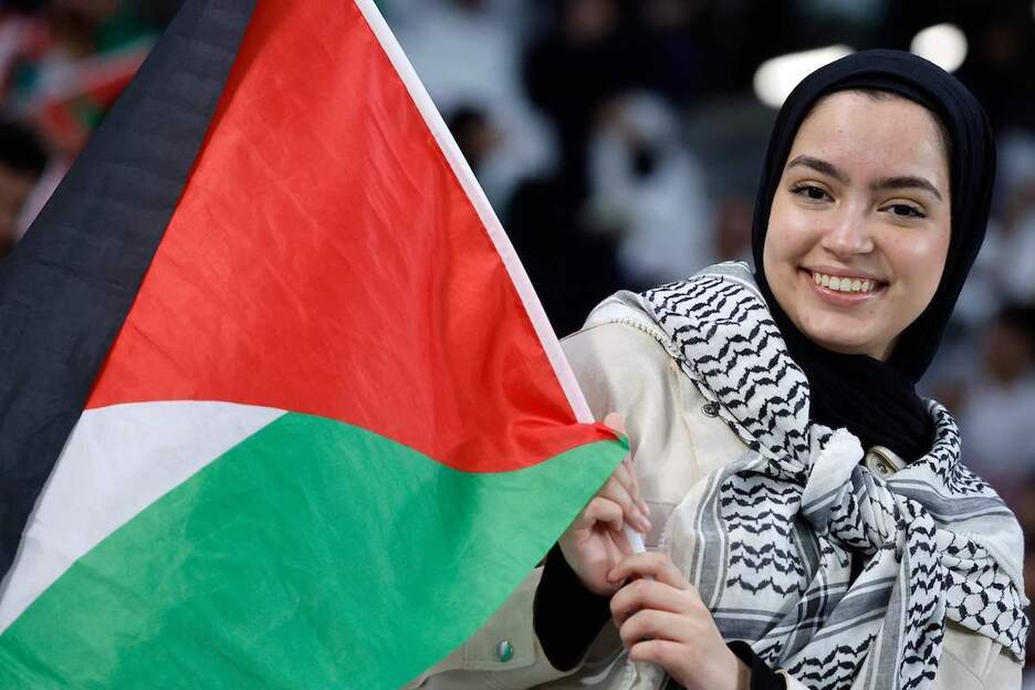 Beste palestinar zale bat, bandera eskuetan zelai barruan.