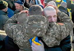 Un militar abraza a dos soldados ucranianos tras el canje de prisioneros.