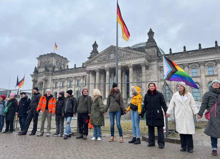 Los manifestantes se cogen de la mano para formar una cadena humana alrededor del edificio del Reichstag en Berlín.