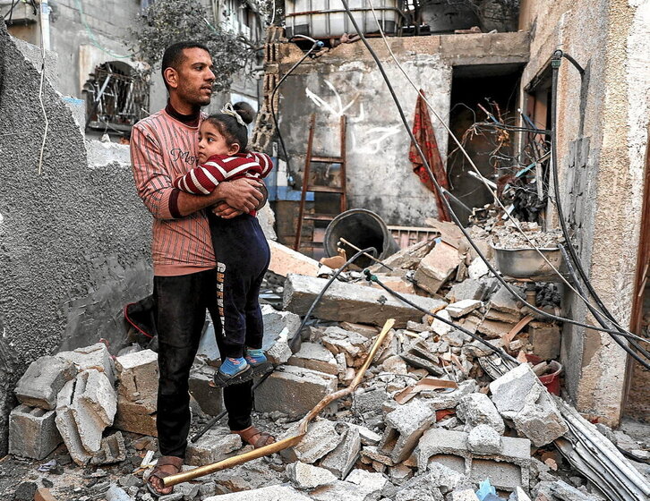 Un hombre sujeta a una niña en una vivienda destruida por una bomba israelí en Rafah.