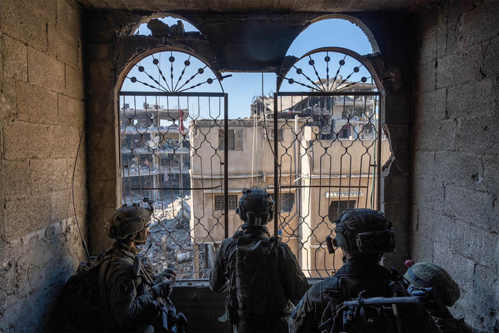  Soldados israelíes contemplan varios edificios destruidos en Gaza.