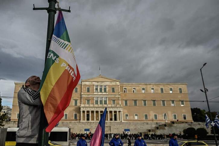 Una personas iza una bandera LGBTQI+ ante el Parlamento griego.