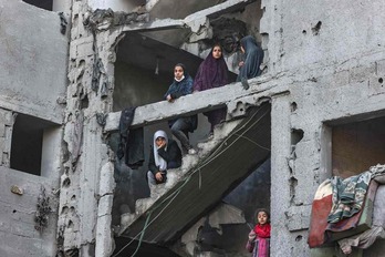 Mujeres y niños observan la destrucción entre las ruinas de un edificio bombardeado en el campo de refugiados de Rafah, al sur de Gaza.