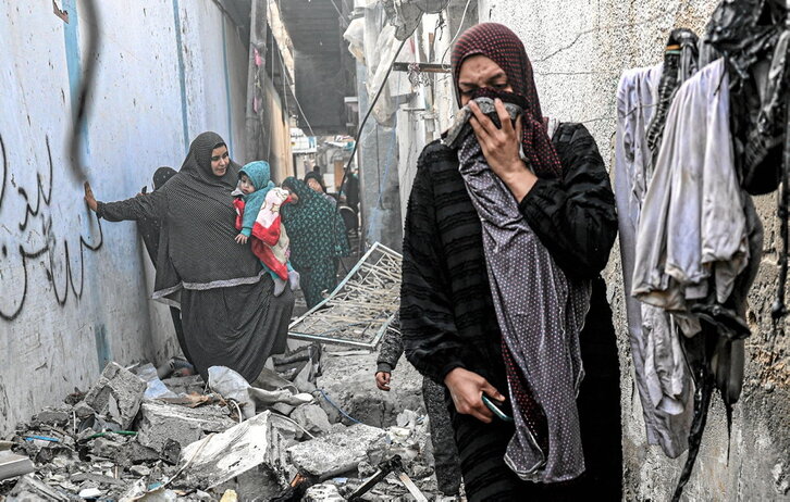 Una mujer se cubre por el olor entre escombros en una callejuela de Rafah tras un bombardeo israelí.