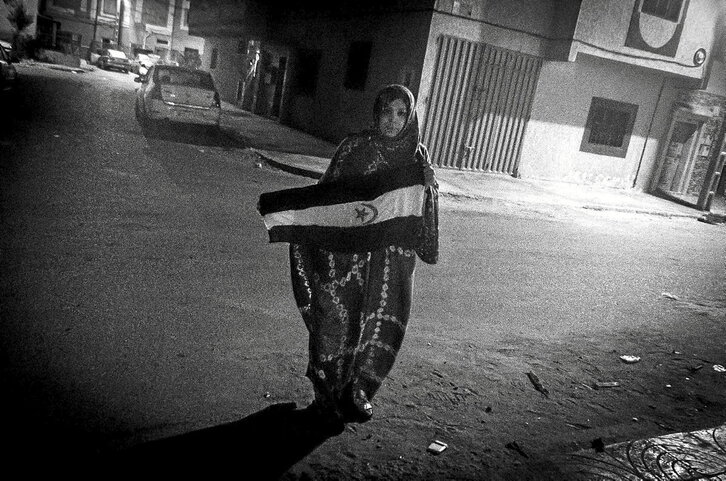 Mahfouda Lafkir, que es una activista de Laayoune, despliega una bandera de la RASD (República Árabe Saharaui Democrática) en una calle cercana a una comisaría de policía para sacar imágenes en pro de la causa saharaui. 