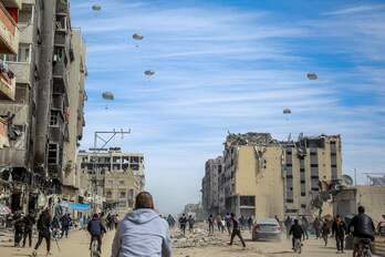 Palestinos corriendo por una calle mientras se lanza ayuda humanitaria desde el aire en la ciudad de Gaza, este viernes.