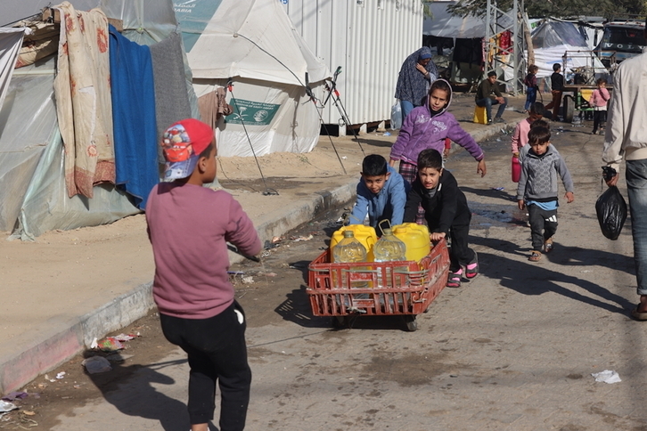 Niños recogen agua en bidones amarillos en el barrio de al-Shaboura en Rafah, sur de Gaza.
