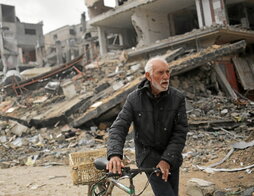 Un hombre empuja su bicicleta entre los edificios destruidos por las bombas israelíes en Jan Yunis.