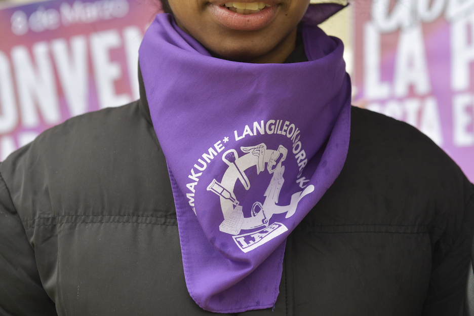 Una joven porta un pañuelo morado con referencias a la lucha feminista.