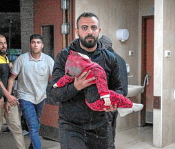 Un hombre lleva a un bebé rescatado de las ruinas de la vivienda de la familia Al-Atrash, en Deir al-Balah.