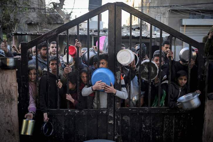 Jóvenes de familias desplazadas en Rafah esperan para obtener algo de comida.