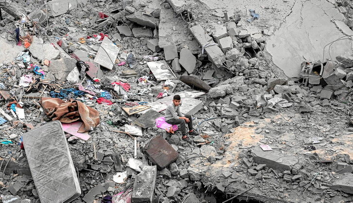 Un chico, sentado entre las ruinas de la vivienda de la familia Al-Atrash, en Deir al-Balah.