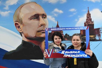 Dos mujeres se fotografían ante un retrato de Putin. 