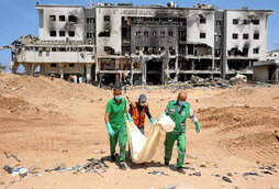 Miembros de Defensa Civil llevan uno de los cuerpos encontrado en el hospital destruido de Al-Shifa.