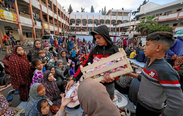 Un chico reparte dulces entre los niños desplazados en una escuela convertida en refugio en Rafah.
