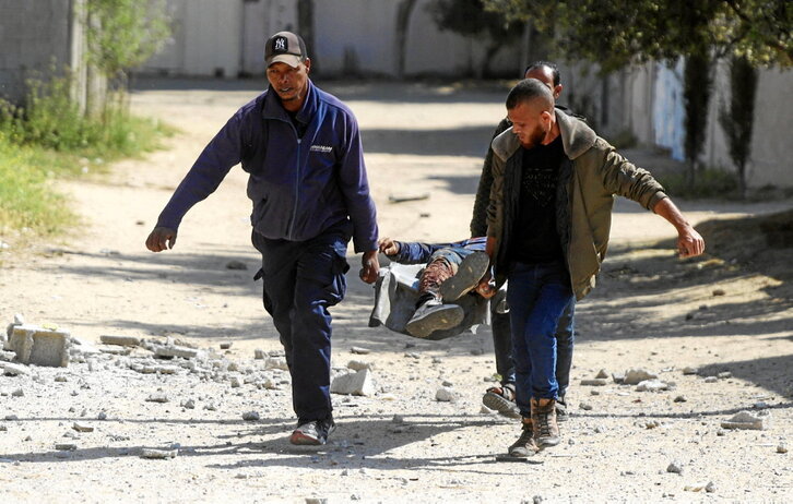 Varios hombres llevan el cuerpo de un hombre tras un bombardeo israelí en el campo de refugiados de Nuseirat.