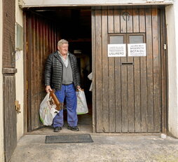 Julián Gurrutxaga sale de su casa con algunas de sus pertenencias en bolsas de plástico.