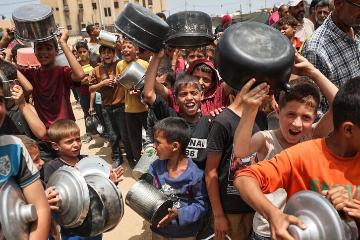 Niños palestinos hacen cola en un reparto de comida en Rafah.