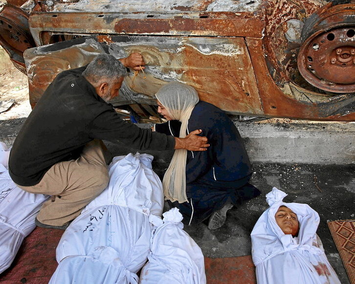 Un hombre y una mujer lloran ante los cuerpos de familiares  muertos en Yabalia.