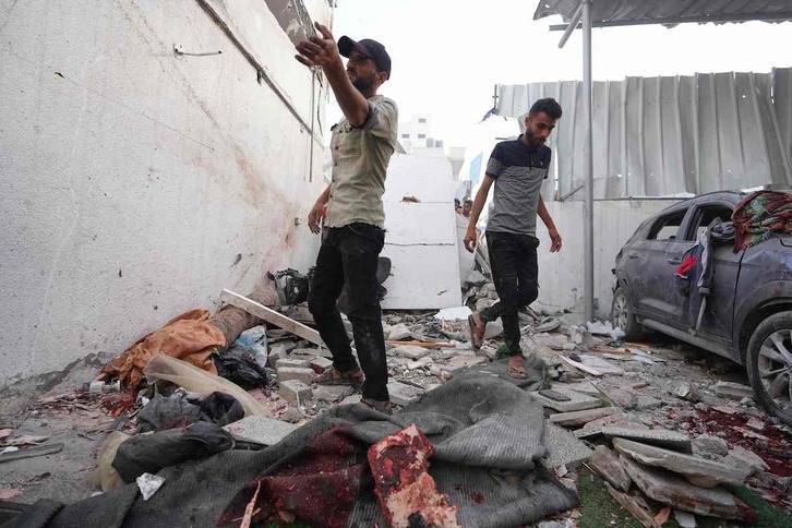 Dos palestinos inspeccionan los daños provocados por un cohete israelí en Nuseirat (Gaza).