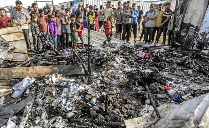 Niños palestinos observan las tiendas quemadas tras el ataque israelí en el campo de Tal al-Sultan.