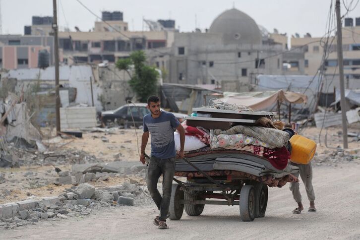 Un joven palestino arrastra colchones y mantas en un carro huyendo  de Rafah a zonas seguras.