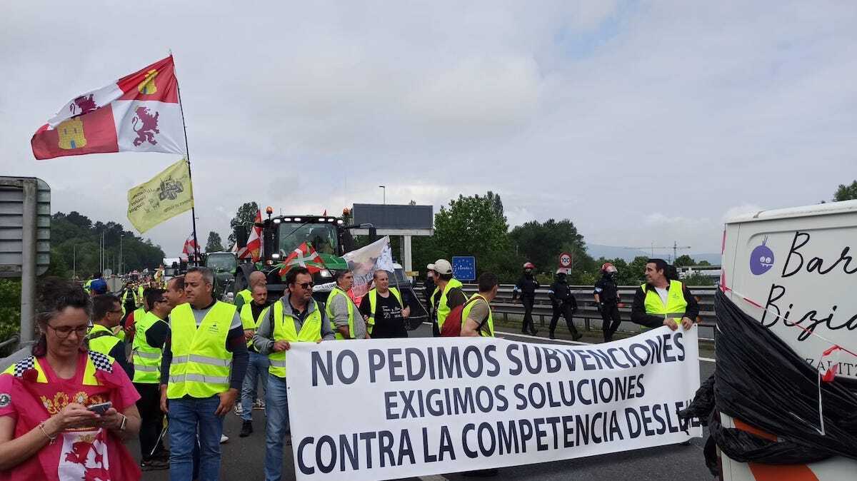 Los agricultores sostienen una pancarta con sus protestas en la muga. (Hegoi BELATEGI)
