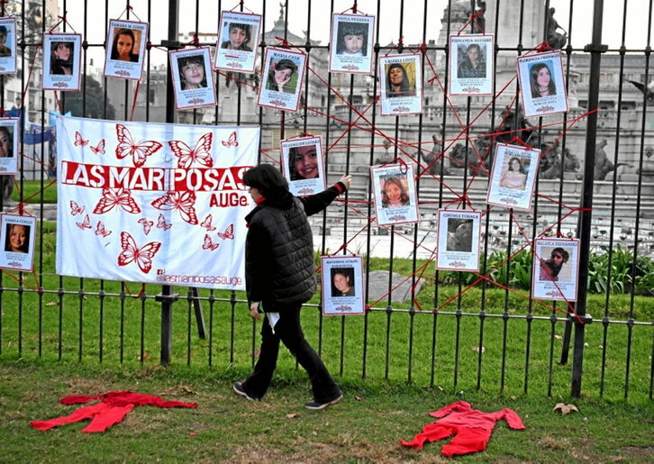 Una mujer pasa en Buenos Aires junto a retratos de desaparecidas.
