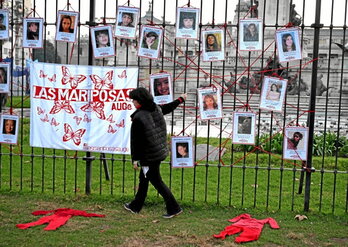 Una mujer pasa en Buenos Aires junto a retratos de desaparecidas.