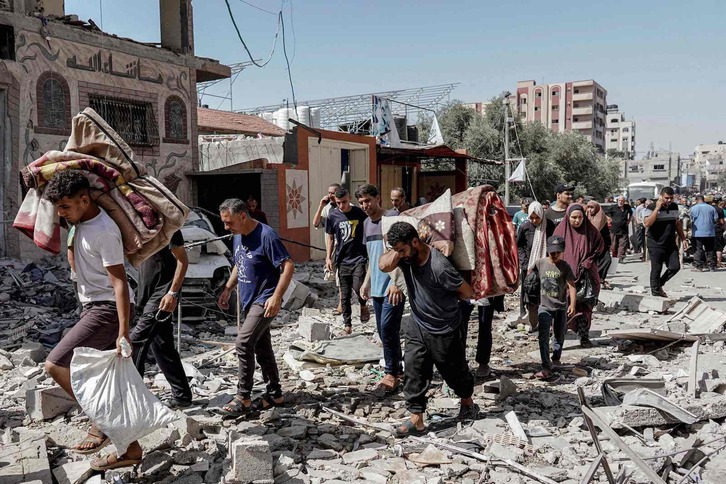 Palestinos caminan sobre los escombros de los edificios destruidos tras la operación de las Fuerza s Especiales isaraelíes en Nuseirat.