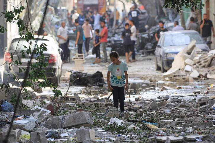 Una adolescente camina sobre las ruinas dejadas por los bombardeos del sábado en Gaza.