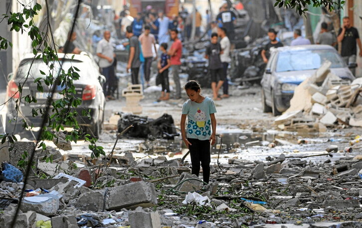 Una adolescente camina sobre las ruinas dejadas por los bombardeos del sábado en Gaza.
