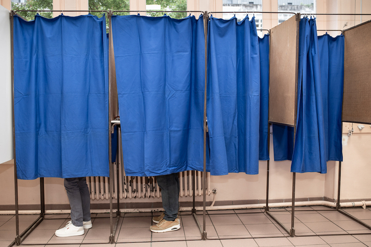 Electores preparan su voto en dos cabinas de un colegio electoral, el 9 de junio en Baiona.