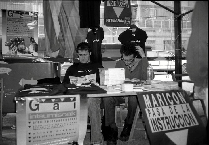 Mesa en el «Intsumiso eguna» de 1999 y cartel de Ehgam que llamaba a la insumisión marica.