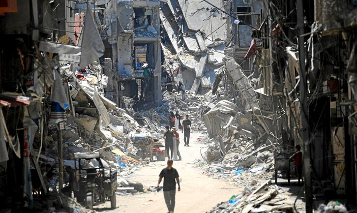 Palestinos, entre edificios destruidos en lo que fue una calle de Jan Yunis.