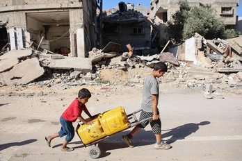 Dos niños transportan agua en Gaza.