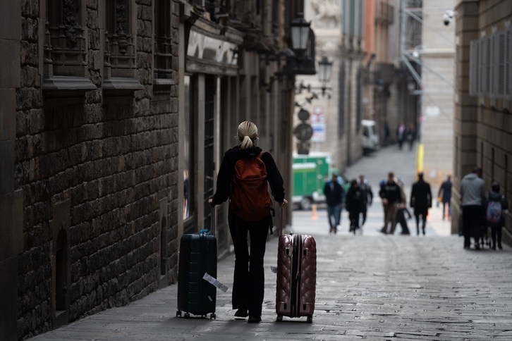 Una mujer con dos maletas por una calle de Barcelona.