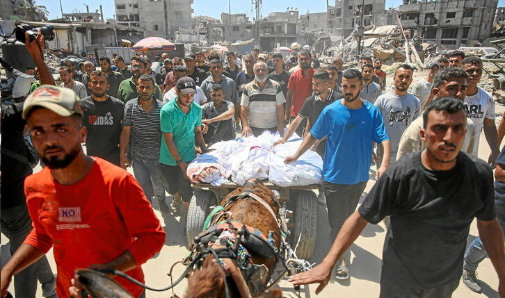 Palestinos trasladan los cuerpos de varios muertos en los bombardeos israelíes contra el barrio gazatí de Al-Tuffah.