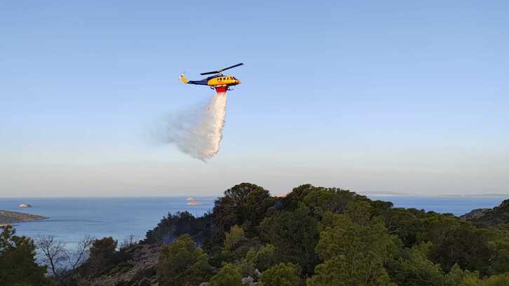Un helicóptero de bomberos descarga litros de agua sobre la isla de Hidra.