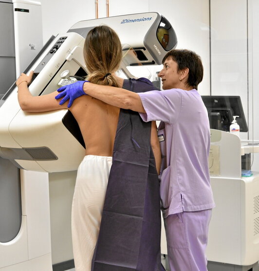 Una paciente es atendida por una profesional sanitaria durante una mamografía.