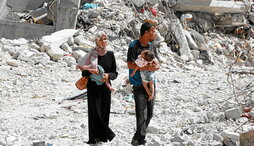 Una pareja palestina, con sus dos hijos, entre las ruinas de Jan Yunis.