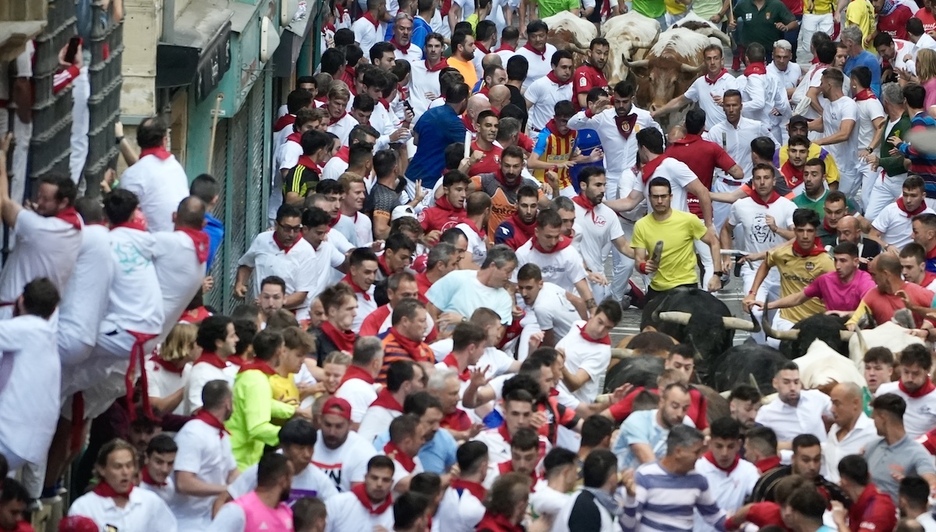Un morlaco se asoma entre la masa humana en la calle principal de la carrera.