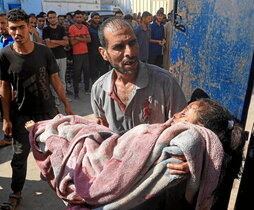 Un hombre con una niña herida en el ataque israelí contra los desplazados de Al Mawasi.