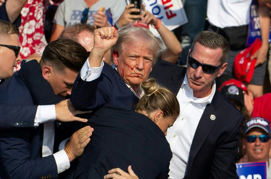 Trump alza el puño mientras la sangre le corre desde la oreja herida.